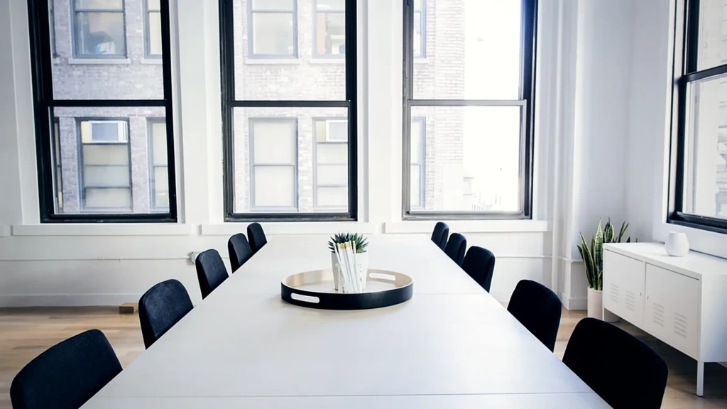 Table de réunion vide devant une rangée de fenêtres